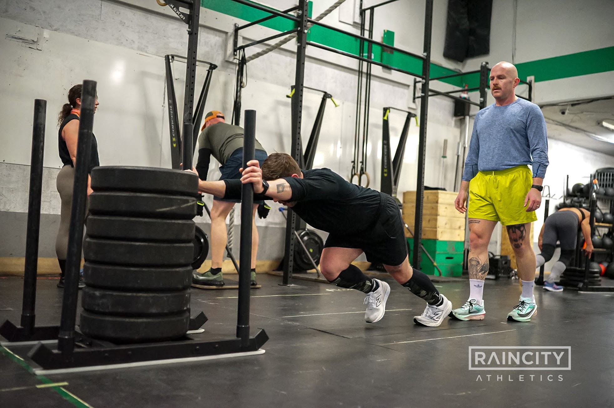 An athlete driving a loaded sled down the floor at a Raincity Half Sim