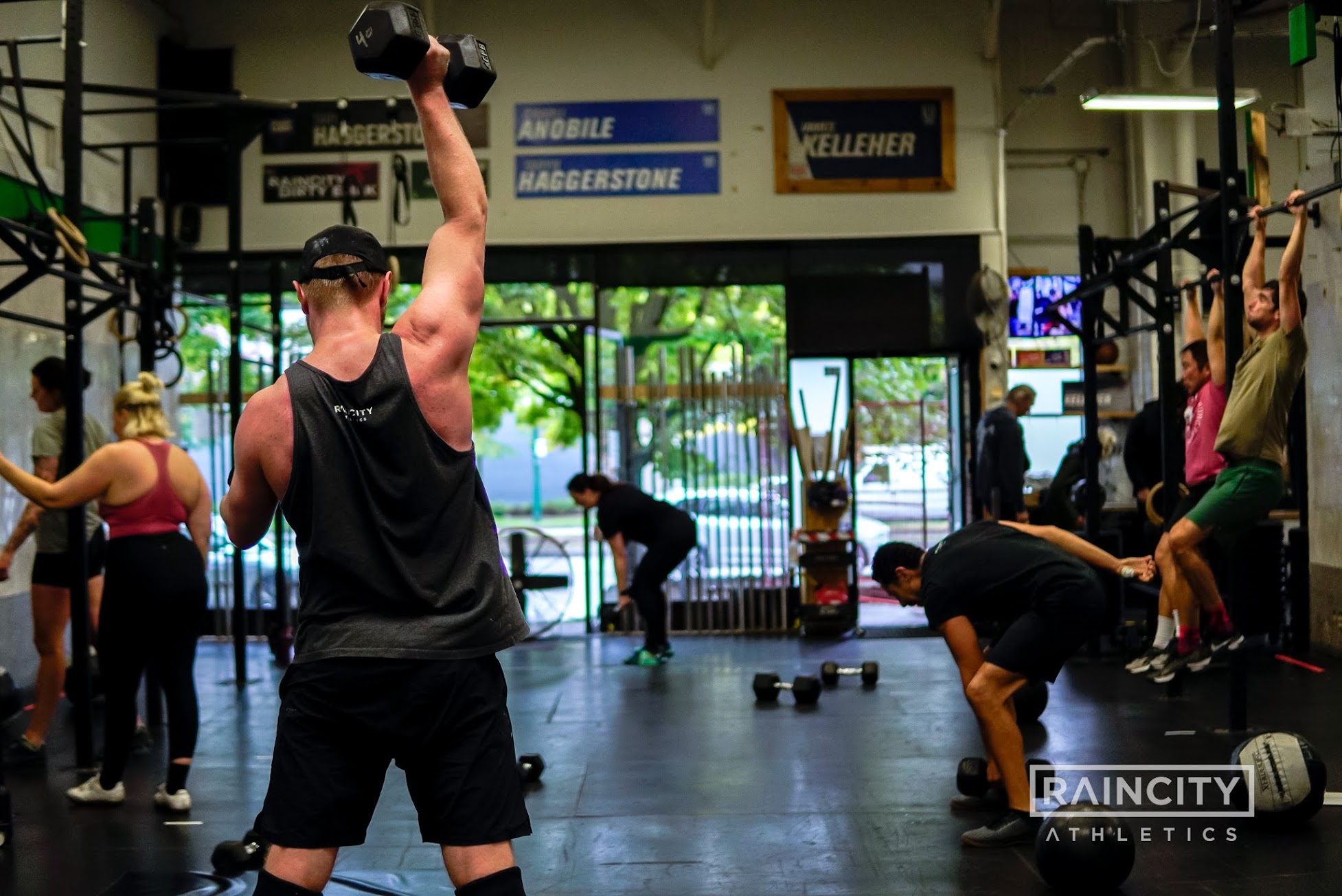 Members training with dumbbells and pull-ups in a group class