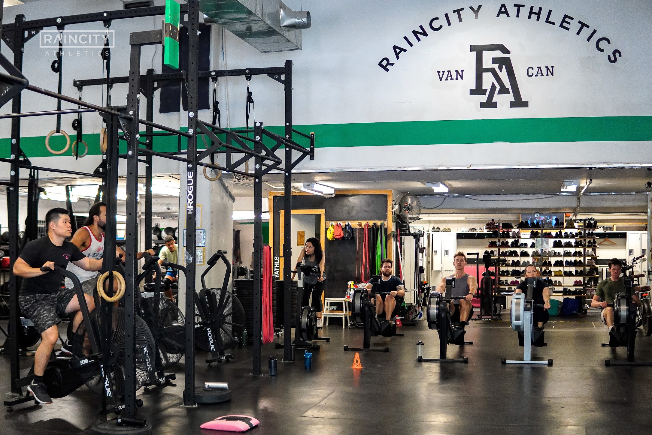 Members of all ages and backgrounds training together on rowers and air bikes during a class