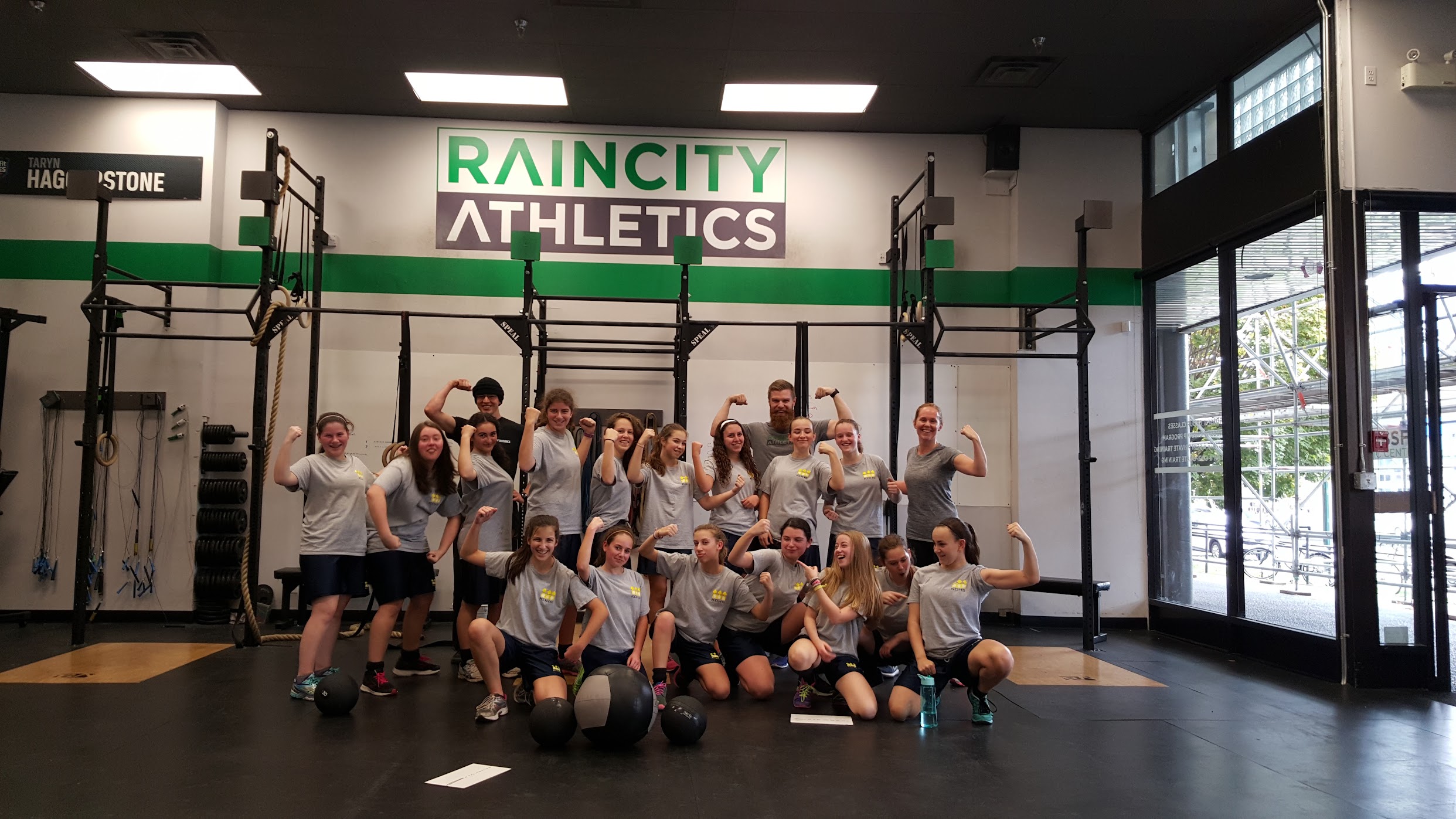 A school group flexing together under the Raincity Athletics logo after a field-trip session