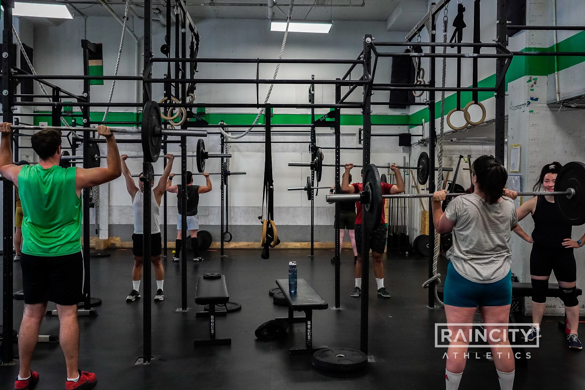 A strength class working barbells in the squat racks
